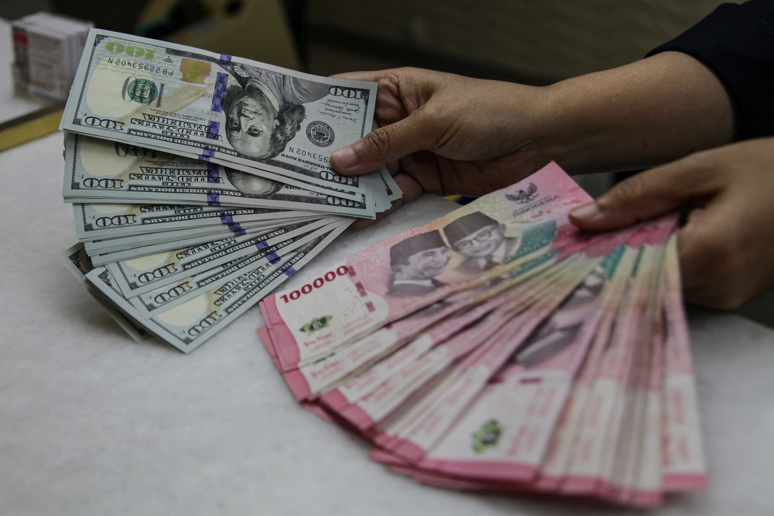Karyawan menunjukkan uang pecahan rupiah dan dolar Amerika Serikat (AS) di gerai penukaran mata uang asing Ayu Masagung, Kwitang, Jakarta. (Sumber: Antara Foto/Darryl Ramadhan/kye) Karyawan menunjukkan uang pecahan rupiah dan dolar Amerika Serikat (AS) di gerai penukaran mata uang asing Ayu Masagung, Kwitang, Jakarta. (Sumber: Antara Foto/Darryl Ramadhan/kye)